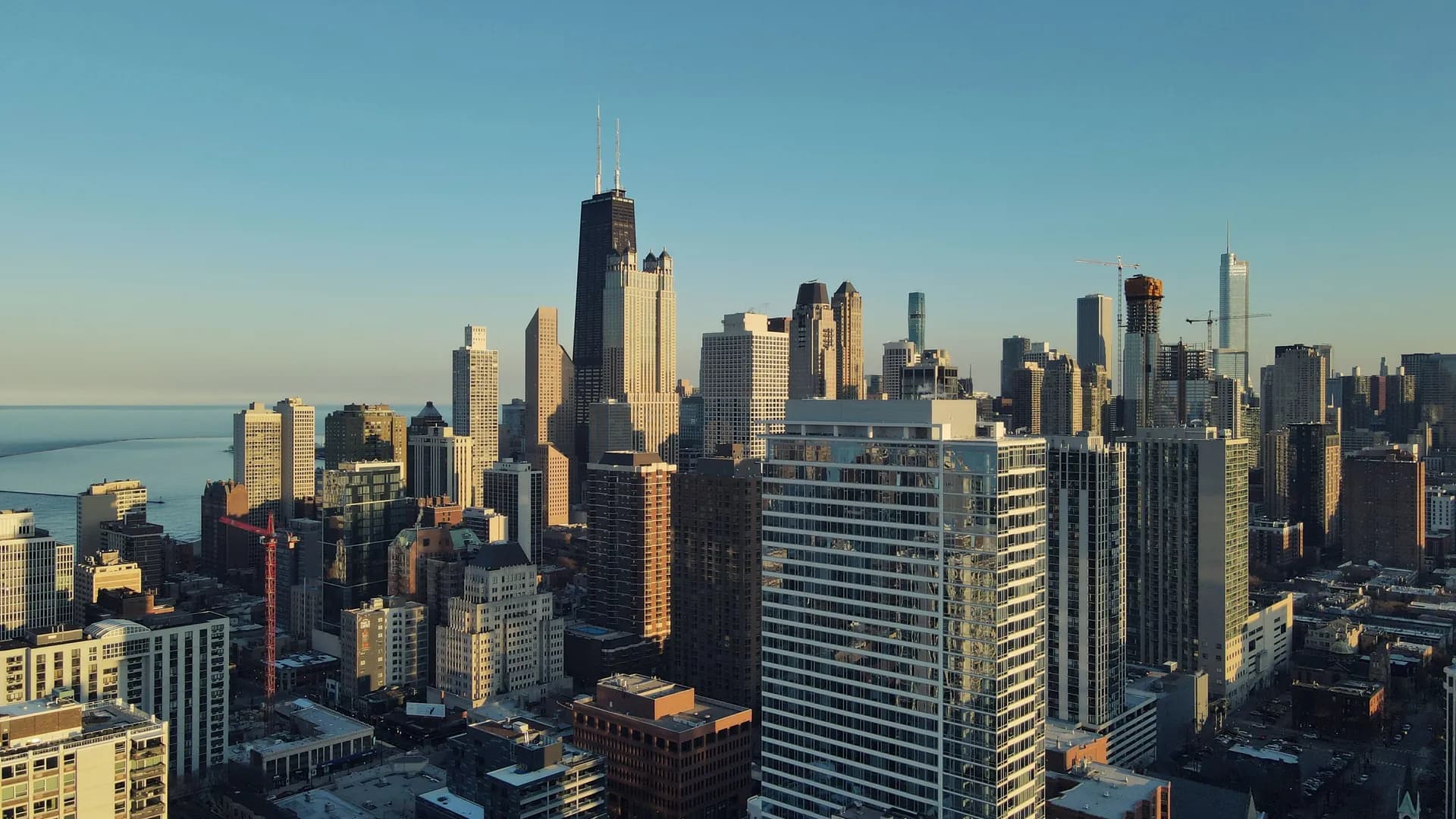 Aerial view of the Chicago skyline at golden hour with the Hancock Center and Lake Michigan on the left