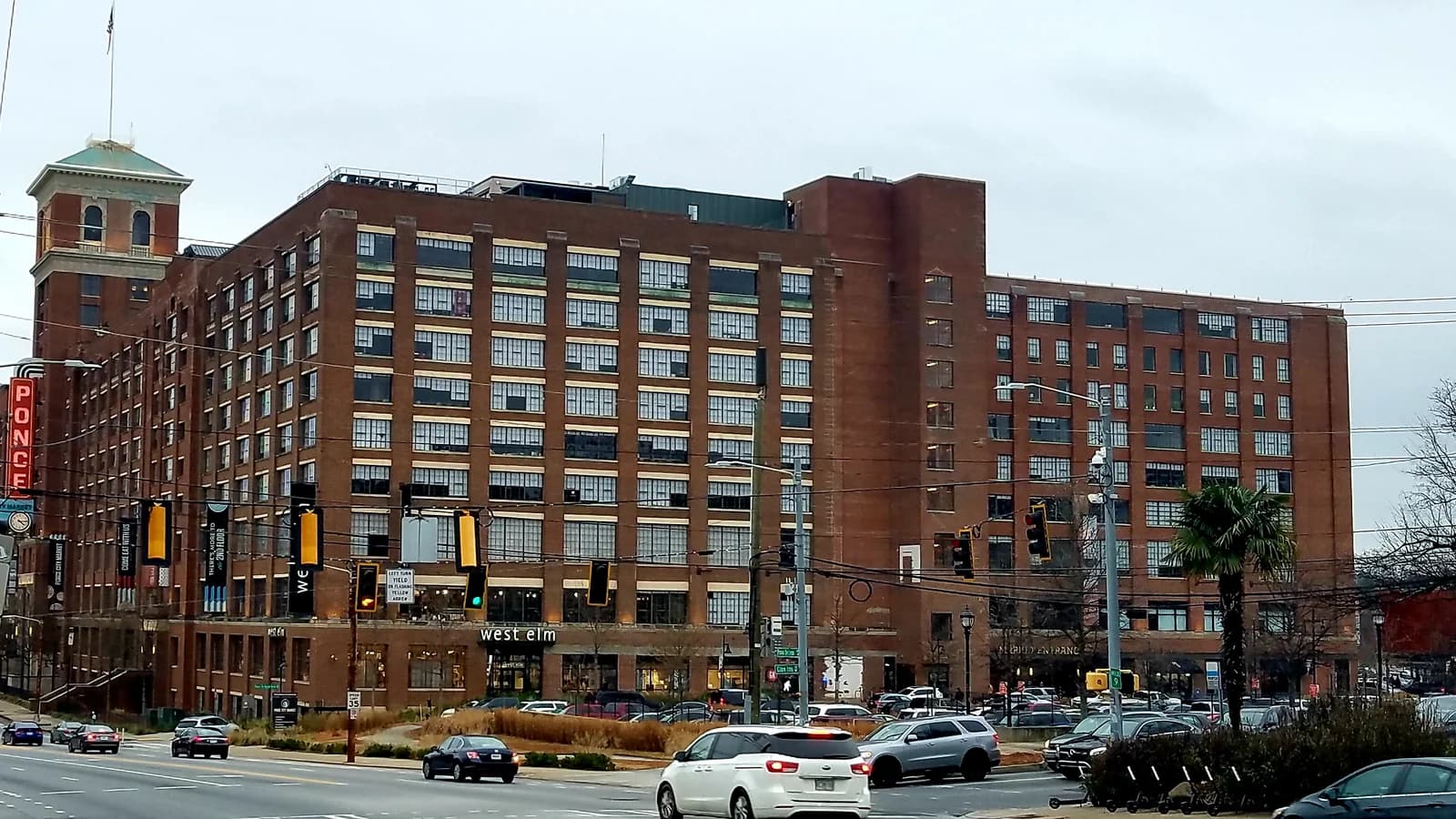 The red brick tower, vertical PONCE sign and long brick facade of Ponce City Market on Ponce de Leon Avenue in Atlanta, with traffic on the street in front