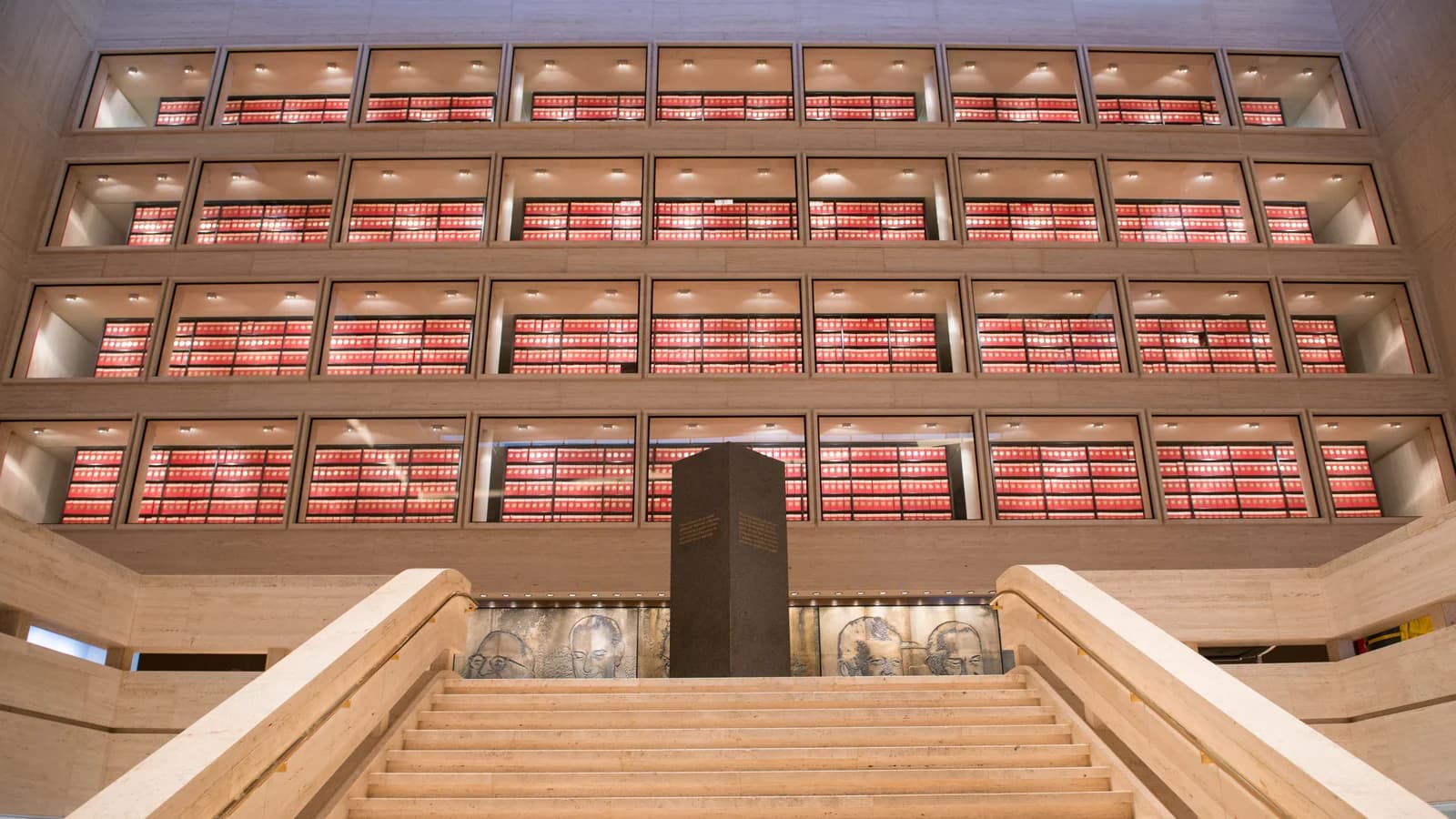 Four stories of red archive boxes behind glass rising above a wide stone staircase in the Great Hall of the LBJ Presidential Library