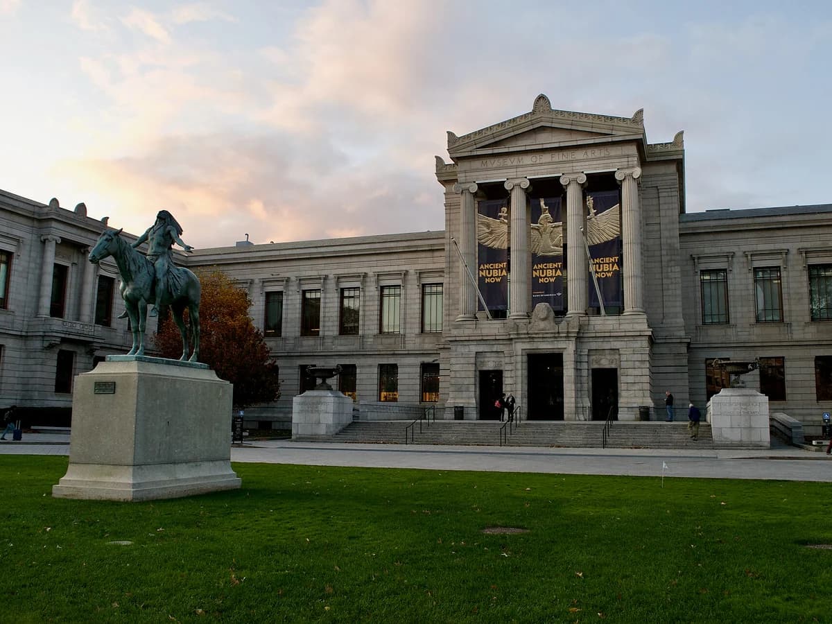 Granite Huntington Avenue facade of the Museum of Fine Arts with its columned entrance portico, and a bronze horseman statue on a pedestal on the front lawn