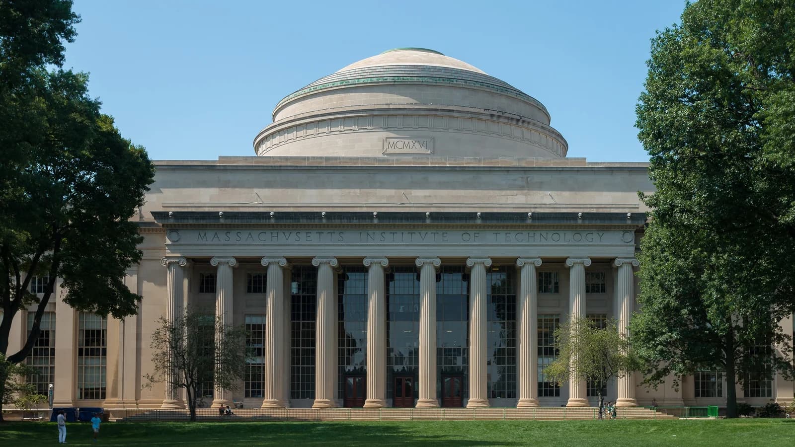 Columned portico and Great Dome of MIT's Building 10 above the green lawn of Killian Court on a clear summer day