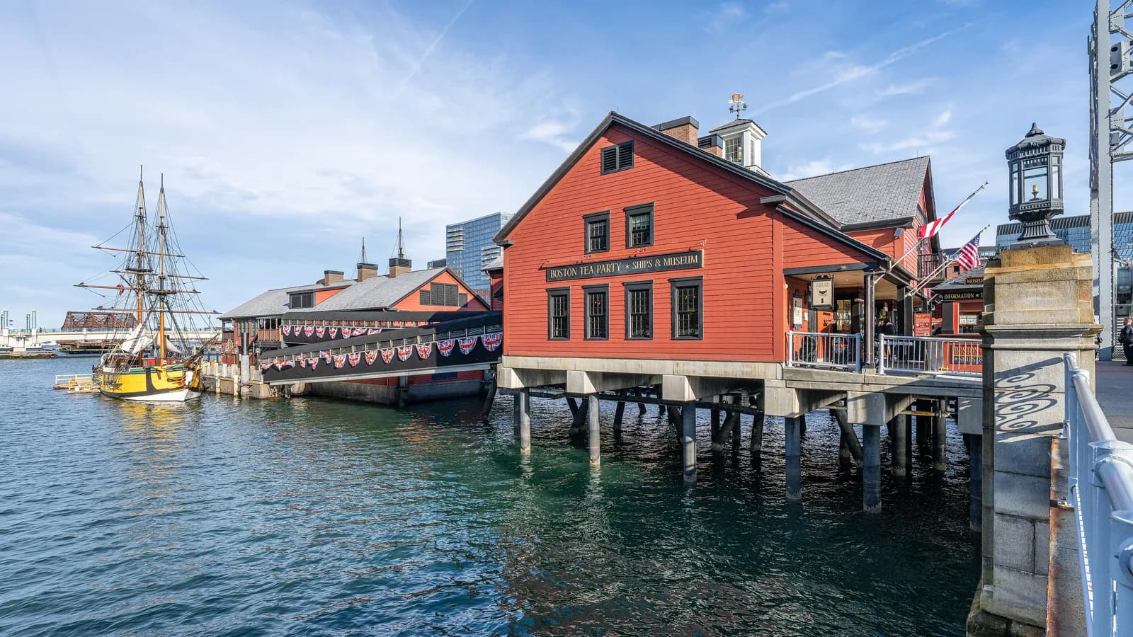 Red clapboard Boston Tea Party Museum on its pier over Fort Point Channel, with a replica tea ship moored beside it