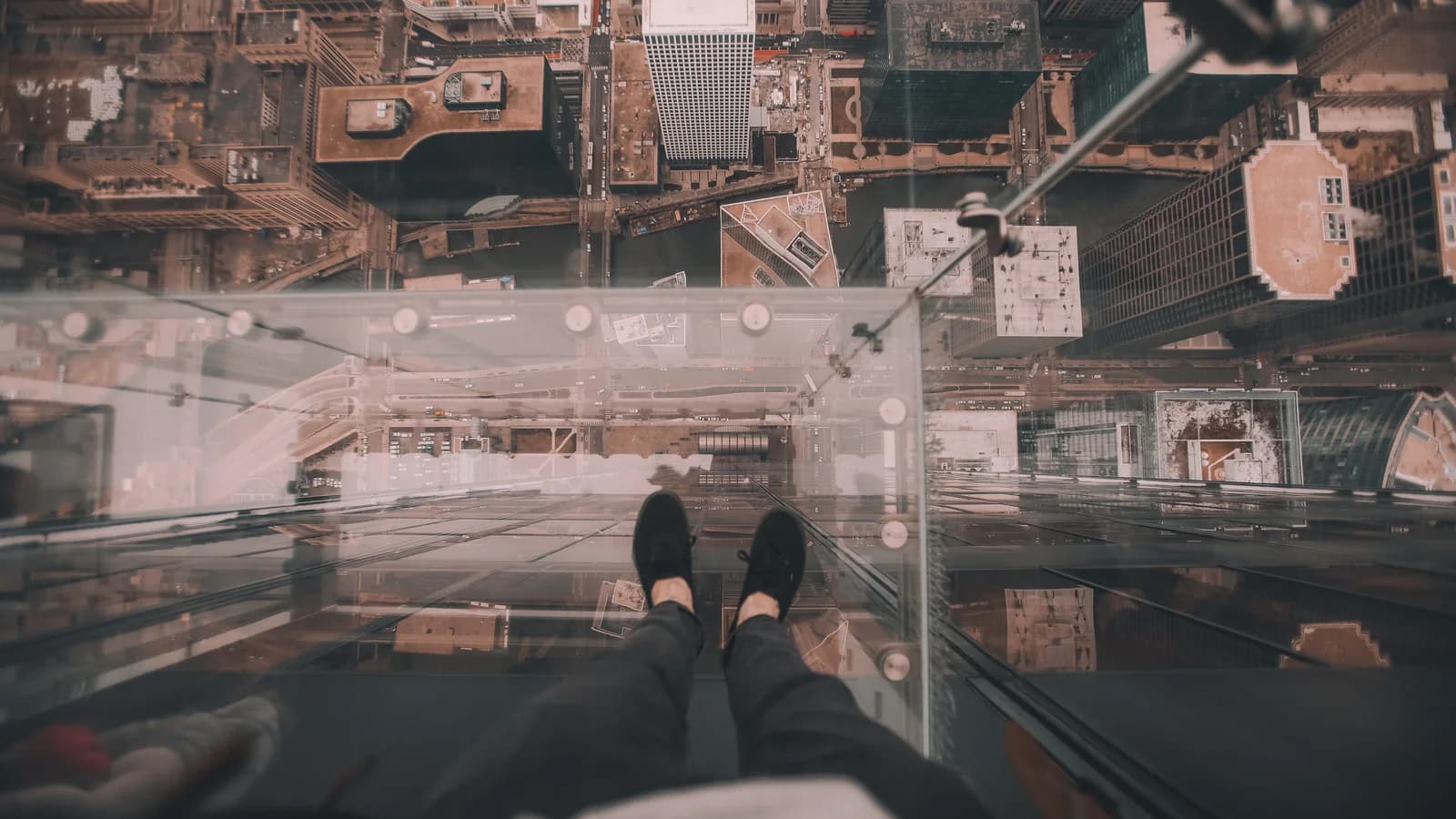 Visitor's feet on the glass floor of The Ledge at Skydeck Chicago, with city streets far below