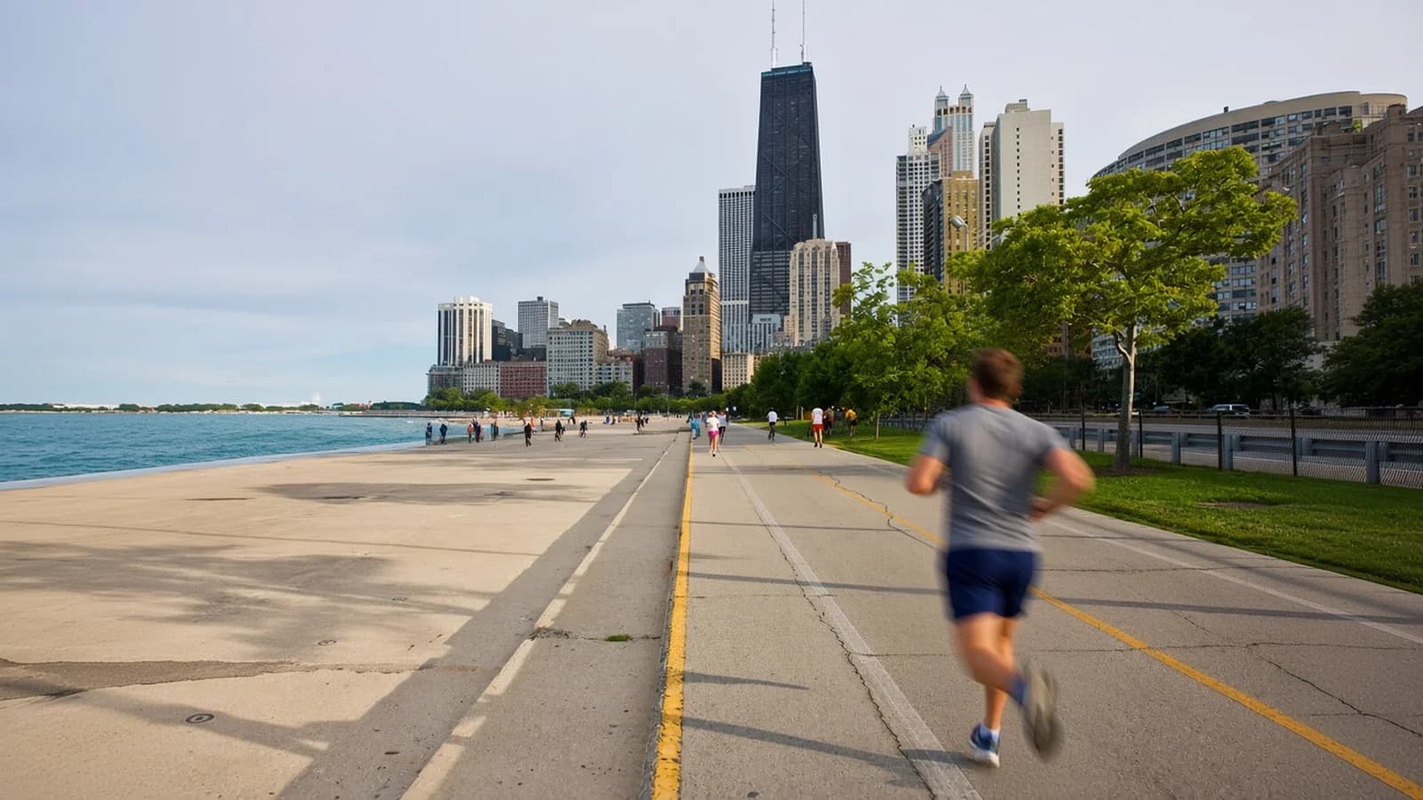 Runner in motion on the Lakefront Trail at Oak Street Beach, with Lake Michigan and the Hancock Center ahead