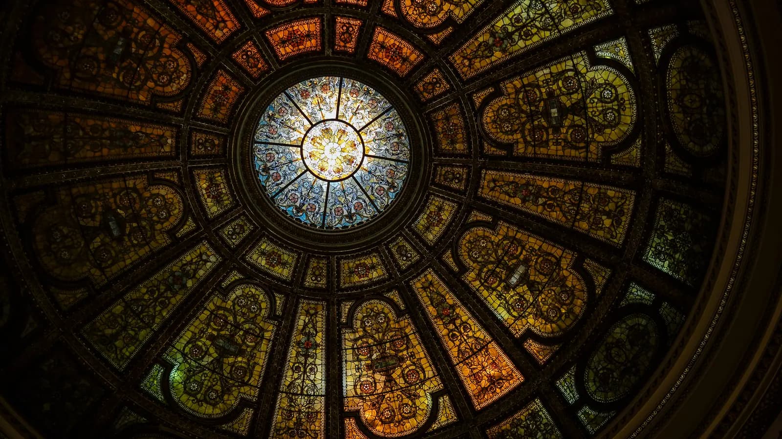 Tiffany stained-glass dome at the Chicago Cultural Center seen from below, glowing amber and blue panels