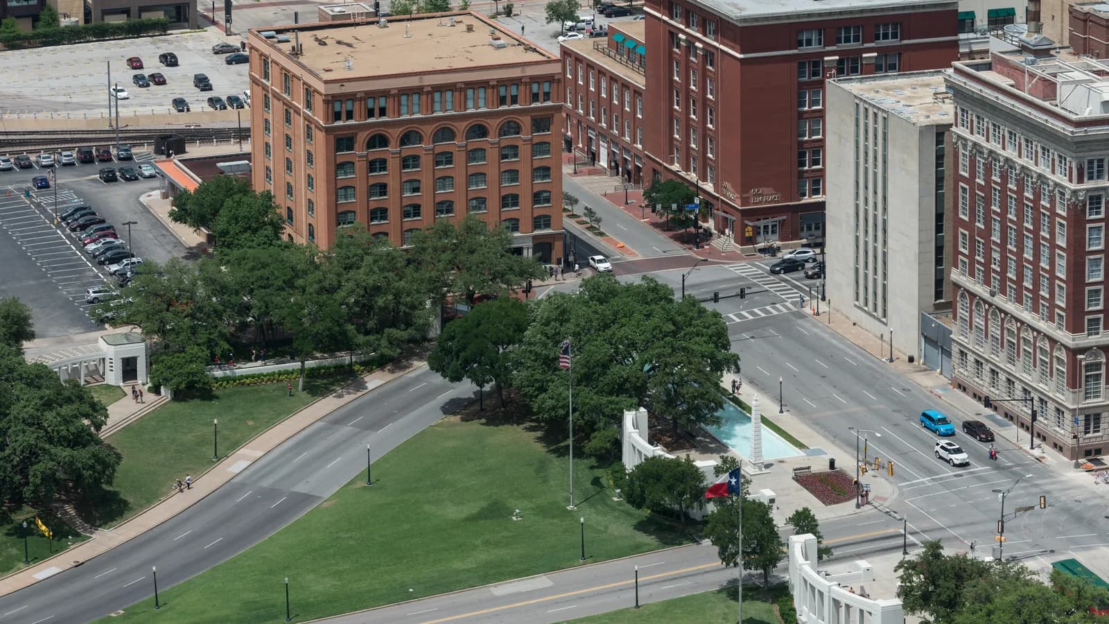 Dealey Plaza from above, with its lawns, curving streets, white pergola and reflecting pool beneath the red brick former Texas School Book Depository