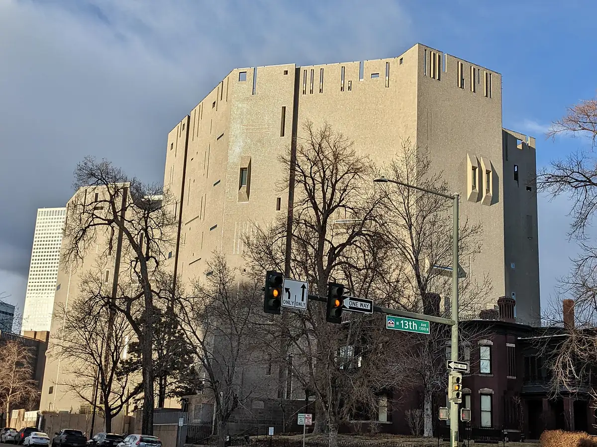 The tall, pale gray Martin Building of the Denver Art Museum, with narrow slit windows and a castle-like top, behind bare winter trees on 13th Ave