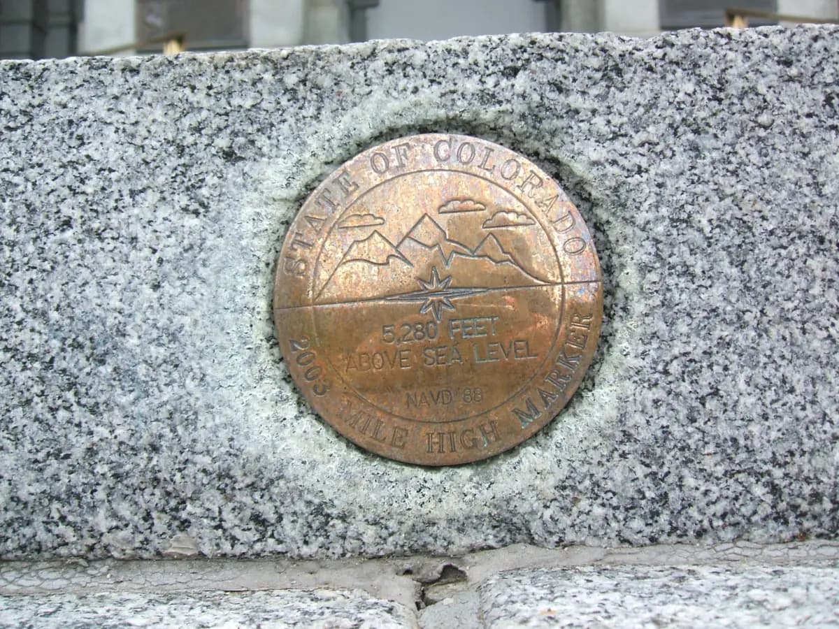 A bronze State of Colorado survey disk reading One Mile High, set into a granite step of the Colorado State Capitol