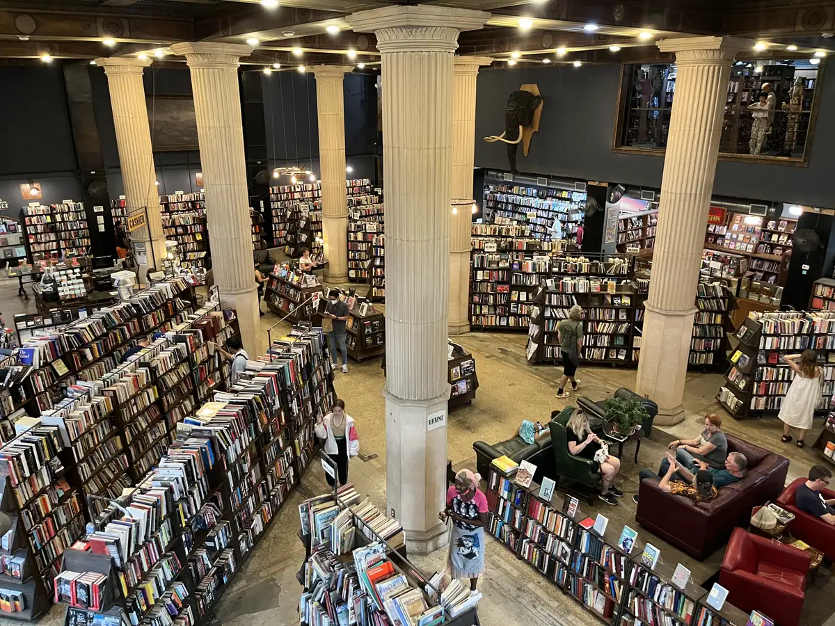 Large hall seen from above, with tall fluted columns, rows of packed bookshelves, leather sofas and a mezzanine of books