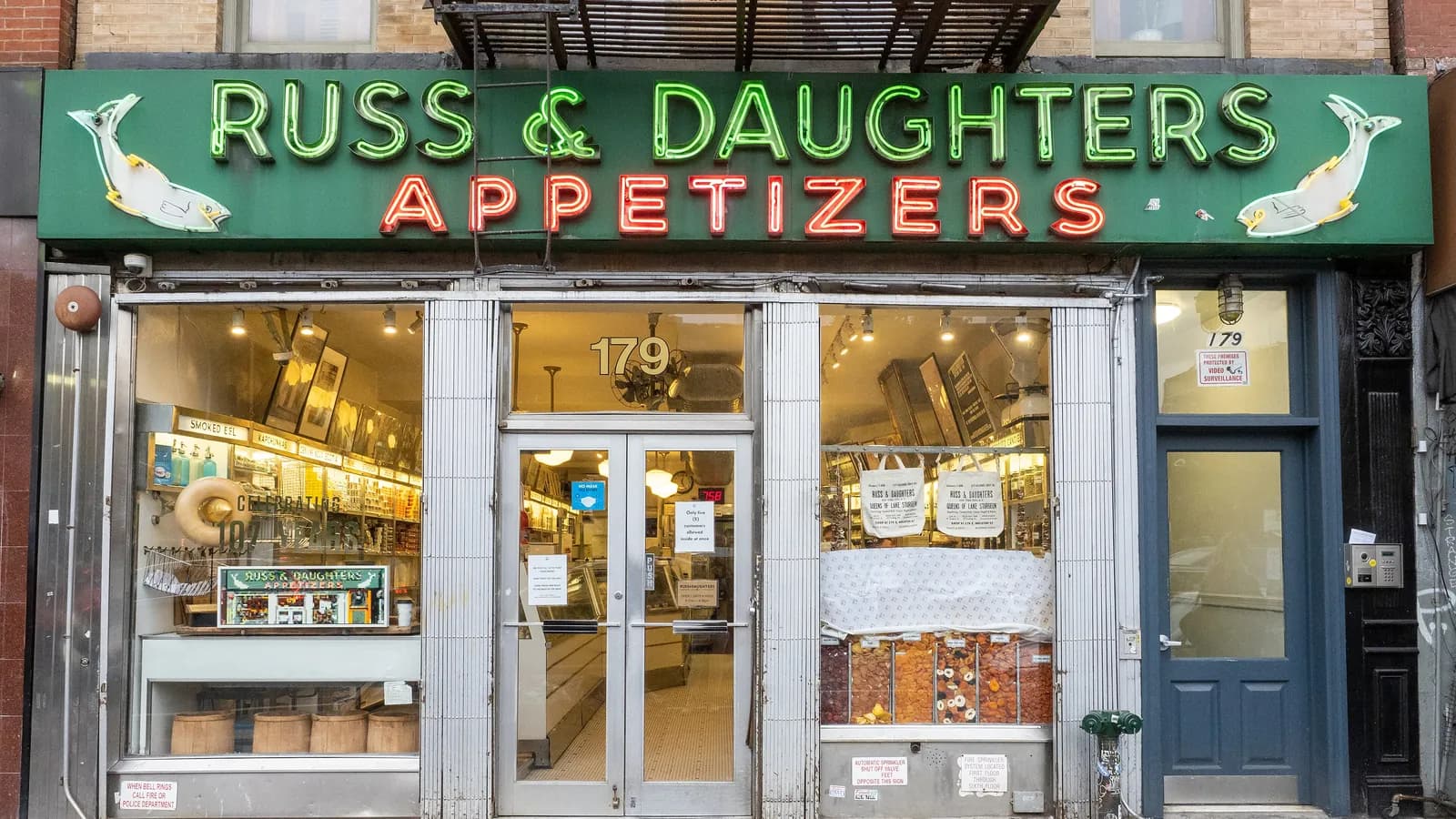 Green and red neon Russ & Daughters Appetizers sign over the steel and glass shopfront on East Houston Street