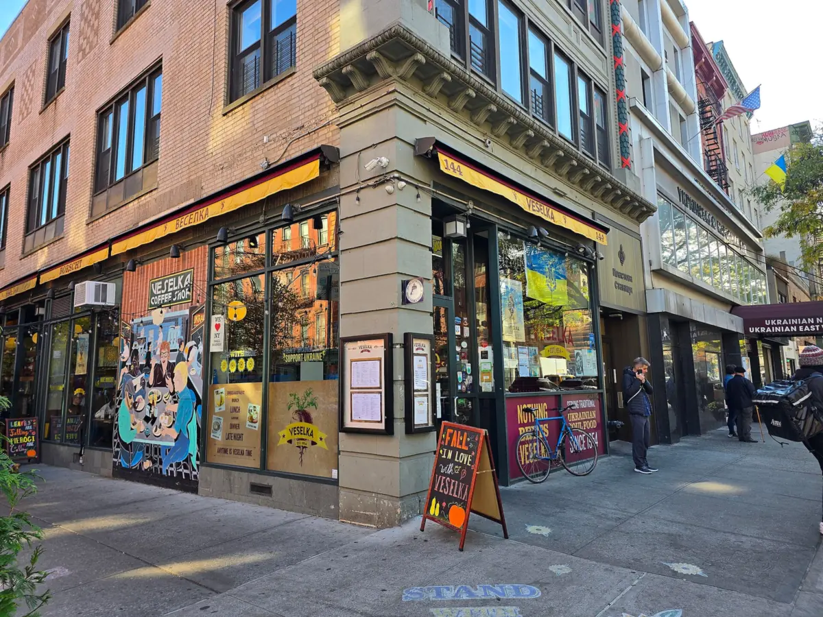 Veselka on the corner of Second Avenue and East Ninth Street, with yellow awnings, a mural on the side windows and a sidewalk chalkboard sign