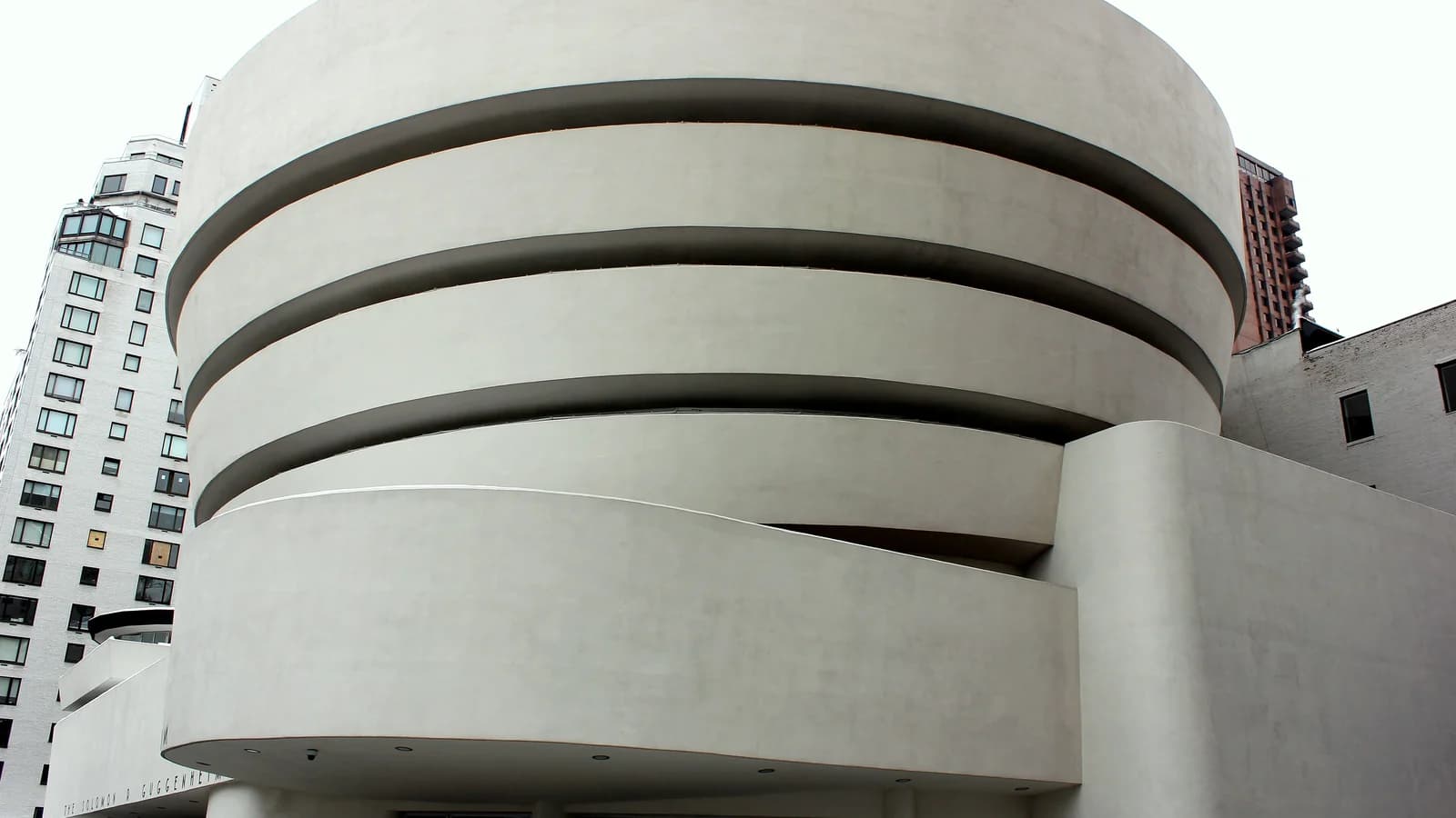 White spiral facade of the Solomon R. Guggenheim Museum on Fifth Avenue seen from street level
