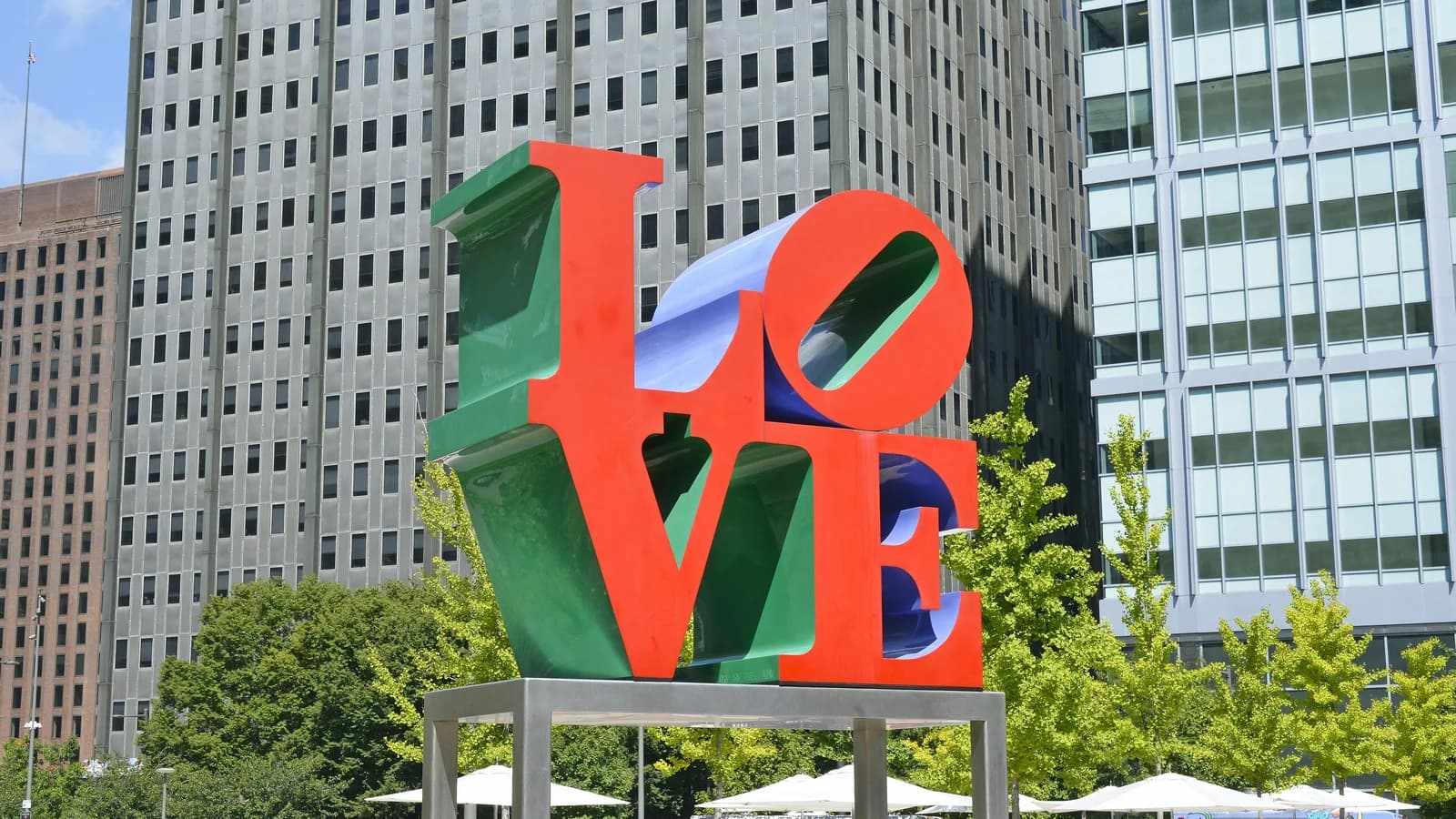Red and green LOVE sculpture in LOVE Park framed by green trees and Center City towers