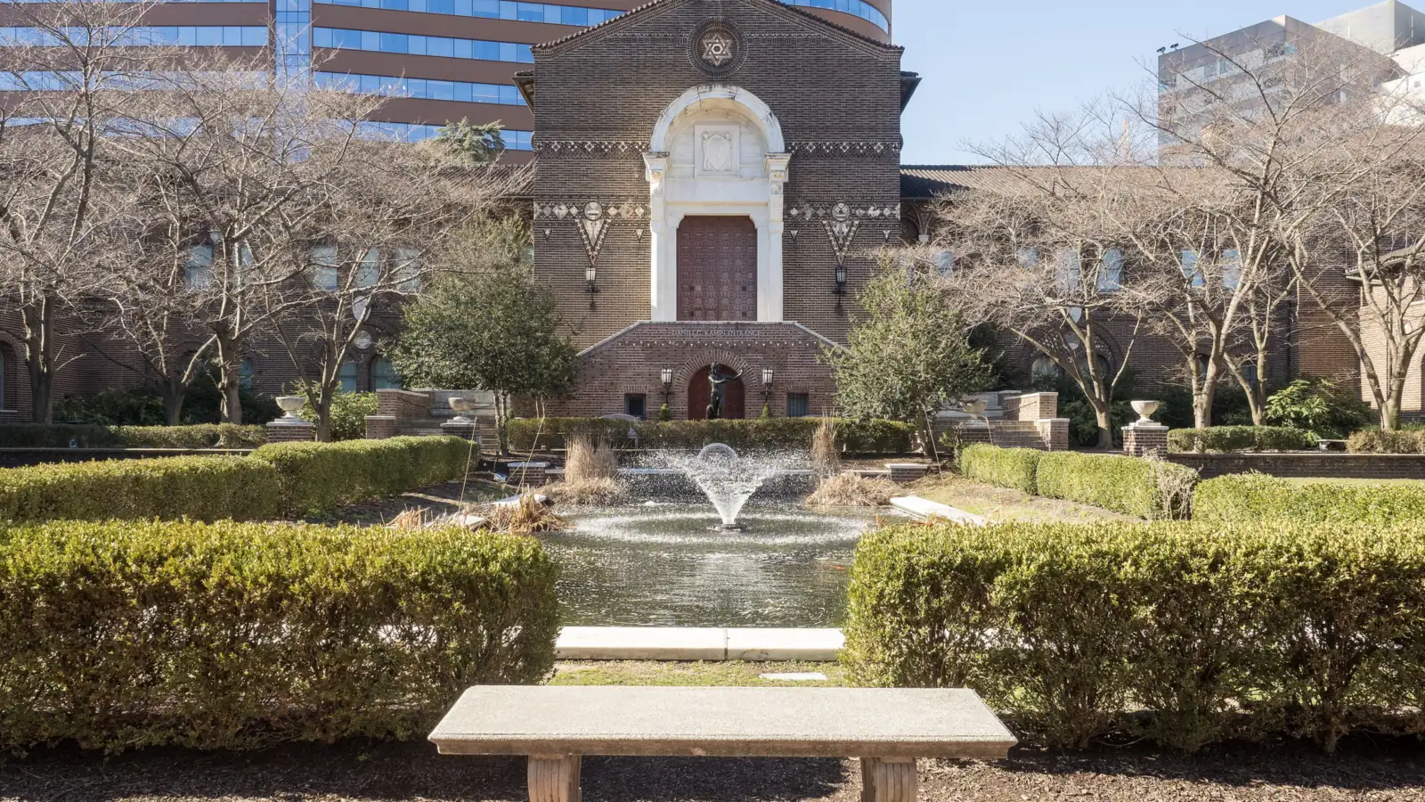 Brick entrance courtyard of the Penn Museum with a fountain pool and trimmed hedges