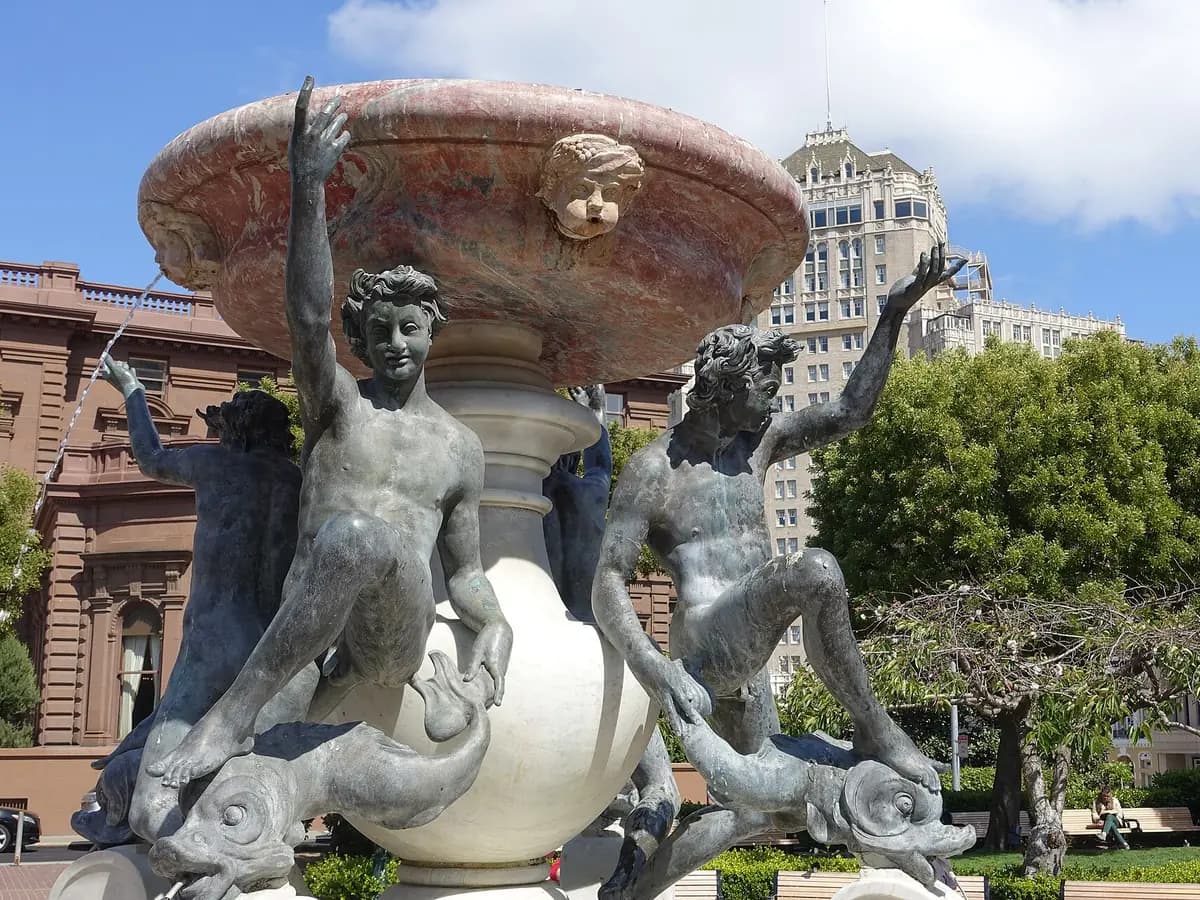 Bronze youths and turtles on the Fountain of the Tortoises in Huntington Park, with the brownstone Pacific-Union Club and a tall apartment building behind