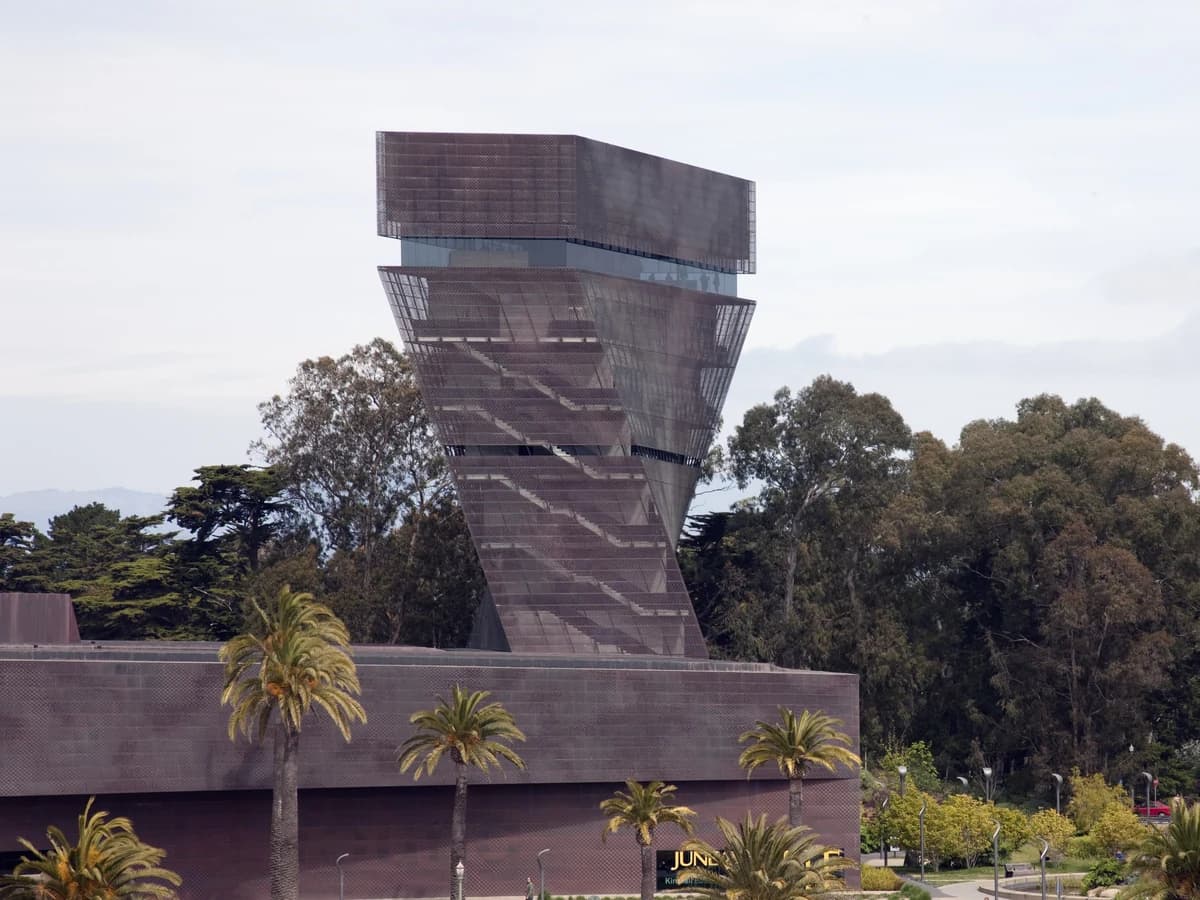 The de Young Museum's twisting Hamon Observation Tower clad in perforated copper, rising above the museum's long copper-skinned wing, palm trees and eucalyptus