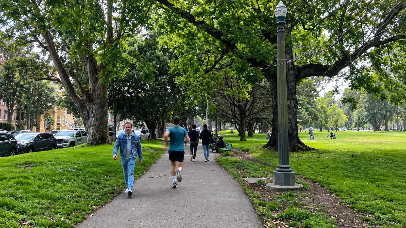 A runner in a teal shirt jogs a paved path through the Panhandle under tall trees, with walkers and green lawns on both sides