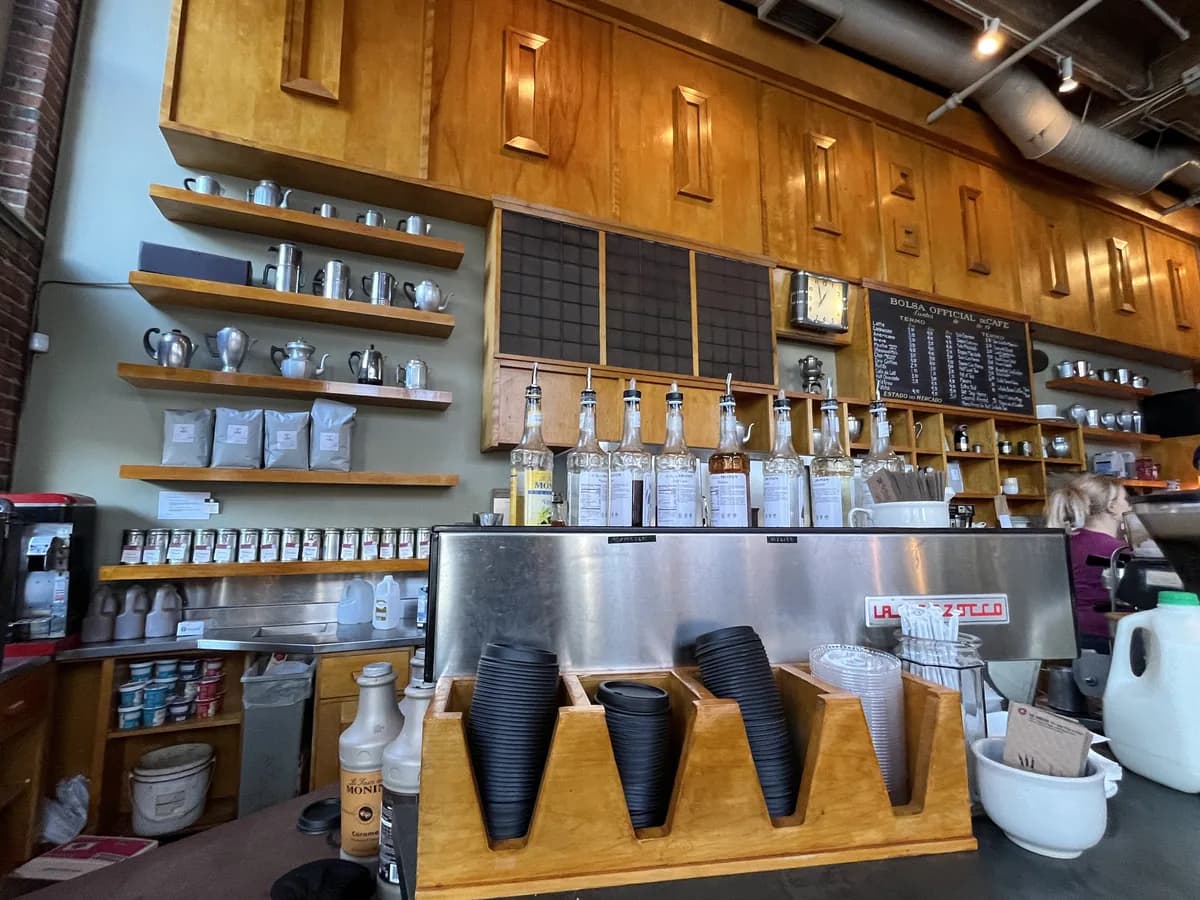 The coffee bar at Zeitgeist Coffee, with wooden shelves of mugs and bags of beans above an espresso counter and glass jars
