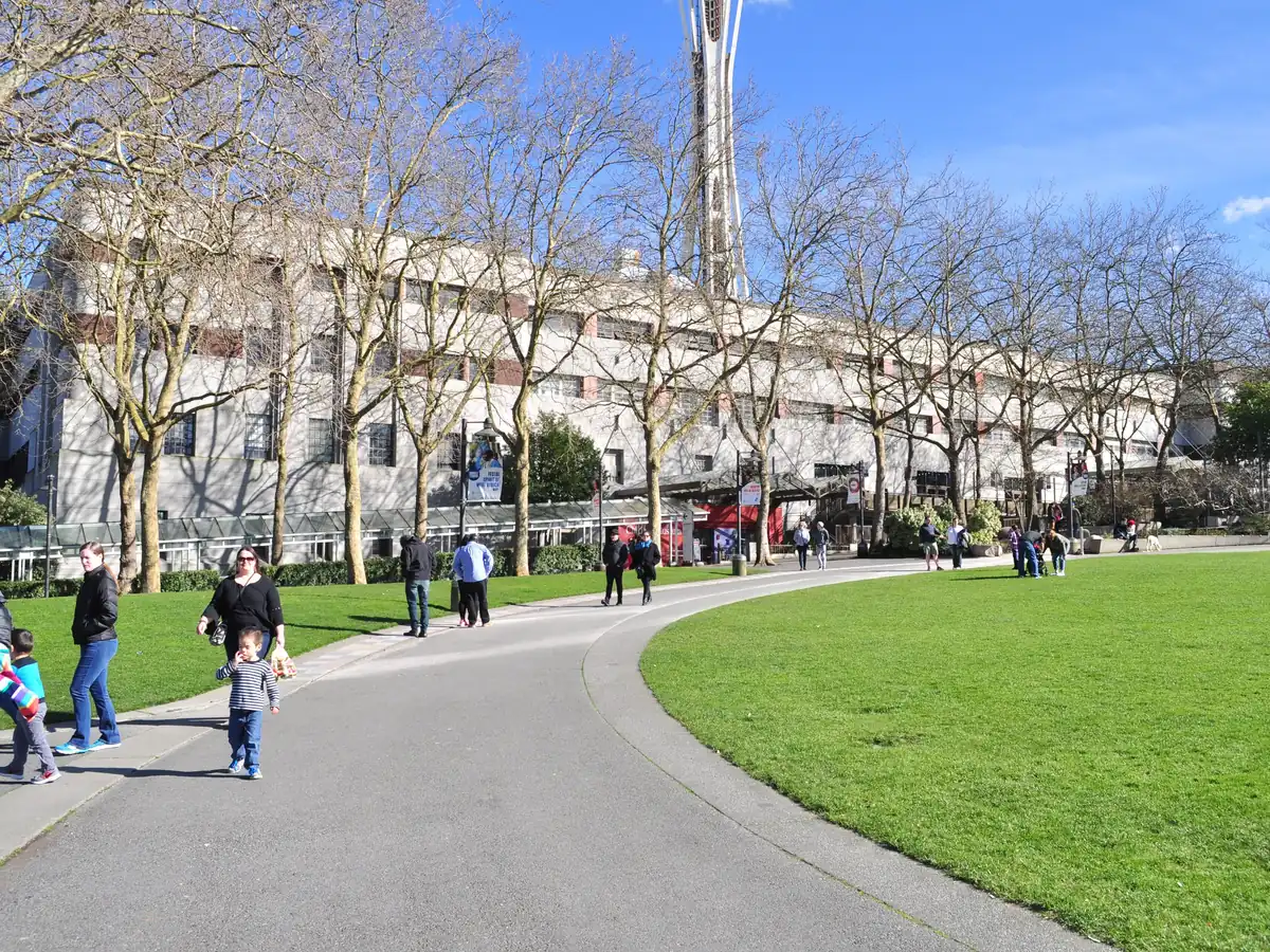 The long pale Armory building at Seattle Center behind a curving path and green lawn, with bare trees and people walking
